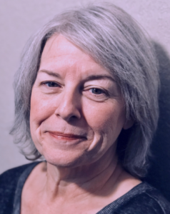 An older white woman with grey hair, smiling.