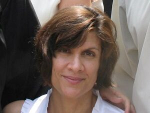 Caucasian female with chin length brown hair and a white blouse.